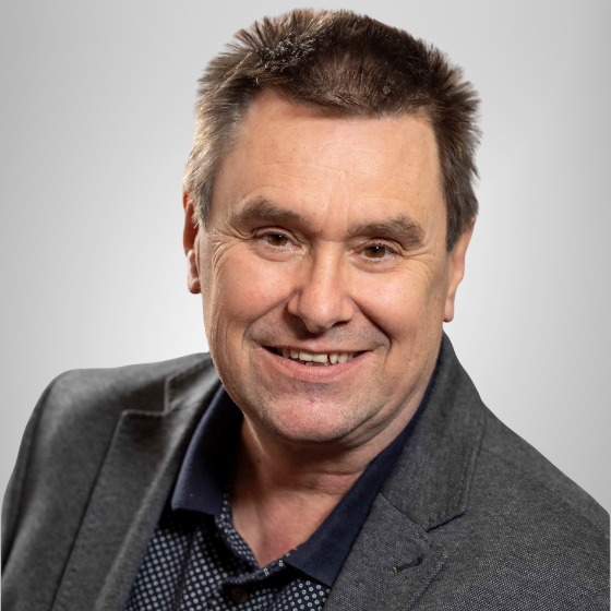 Johannes Matzhold in schwarzem Hemd mit grauem Sako. Er lächelt in die Kamera.