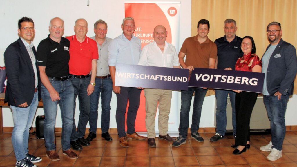 Mitglieder und Funktionäre des Wirtschaftsbundes Ligist stehen für ein Gruppenfoto vor einem Wirtschaftsbund-Roll-up. In der Mitte hält die Gruppe zwei große Schilder mit der Aufschrift „Wirtschaftsbund Voitsberg“.