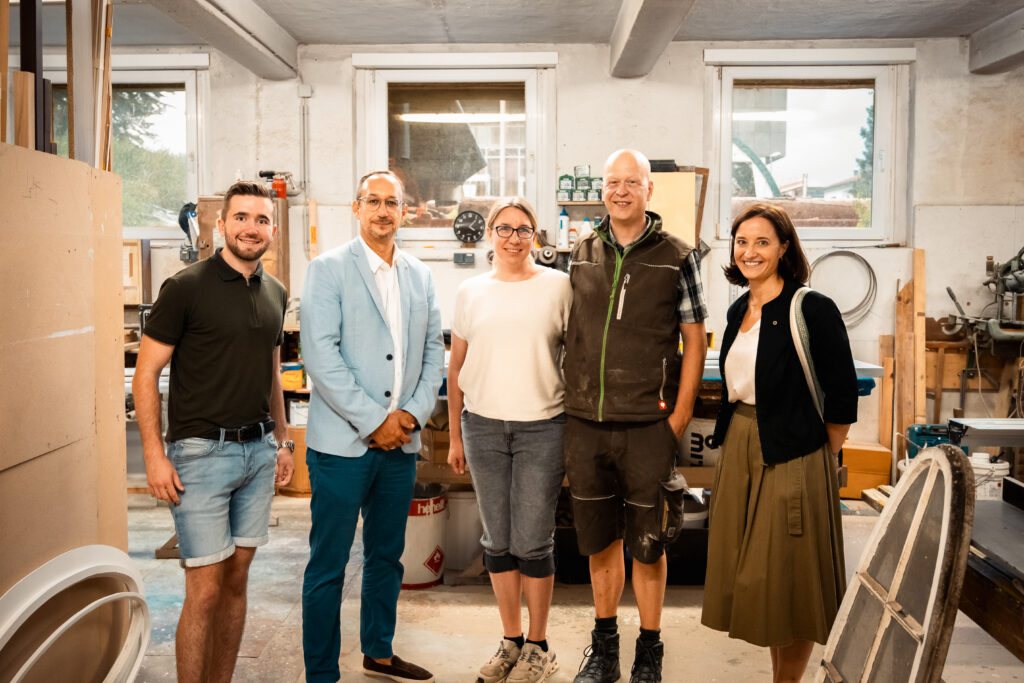Org.-Ref. Simon Bäck, Direktor Jochen Pack und WB-Leoben Obfrau Astrid Baumann stehen gemeinsam mit Inhaber Martin Kölbl und seiner Gattin in der Tischlerei.